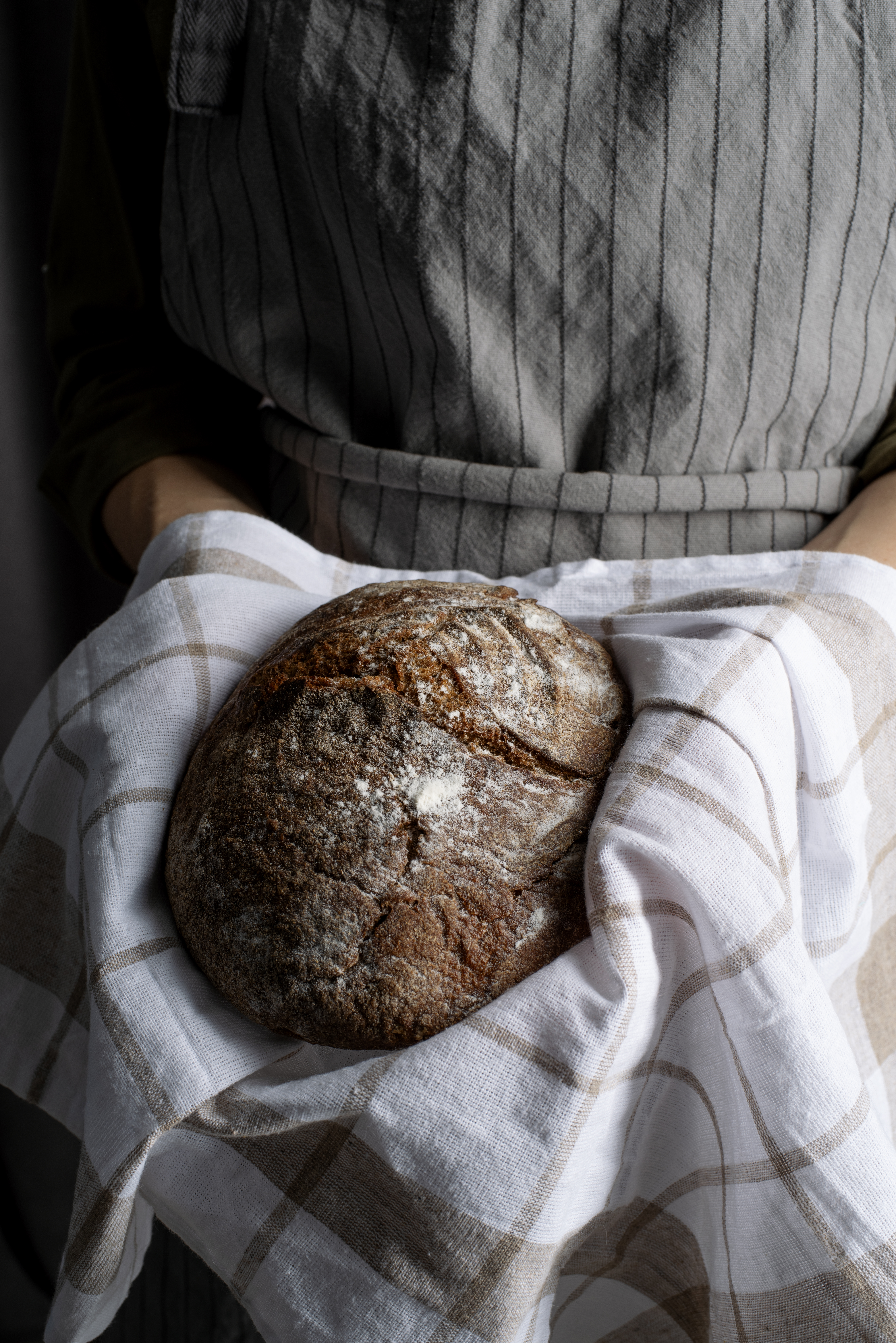 Manos enharinadas amasando masa para pan sobre superficie de madera